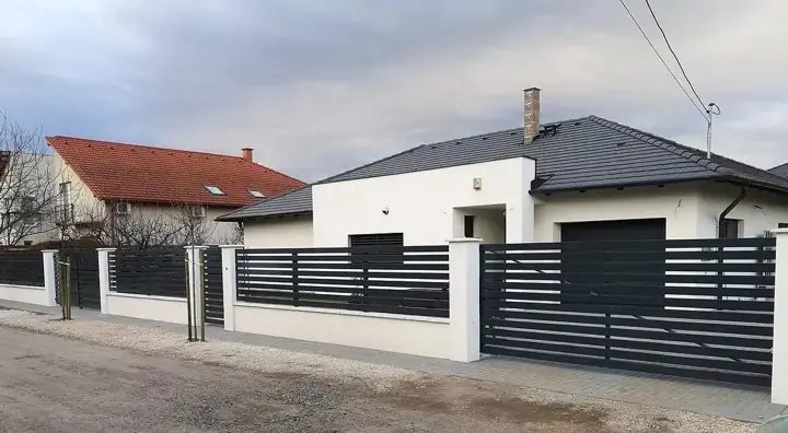 Vakolt fehér pillérek antracit vízszintes léc mezőkkel modern családi ház előtti kerítésen